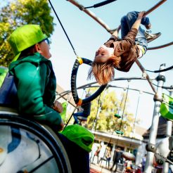 Bild für das Lernmodul "Inklusion" mit einem Spielplatz, auf dem ein Kind klettert und ein weiteres Kind im Rollstuhl dieses beobachtet